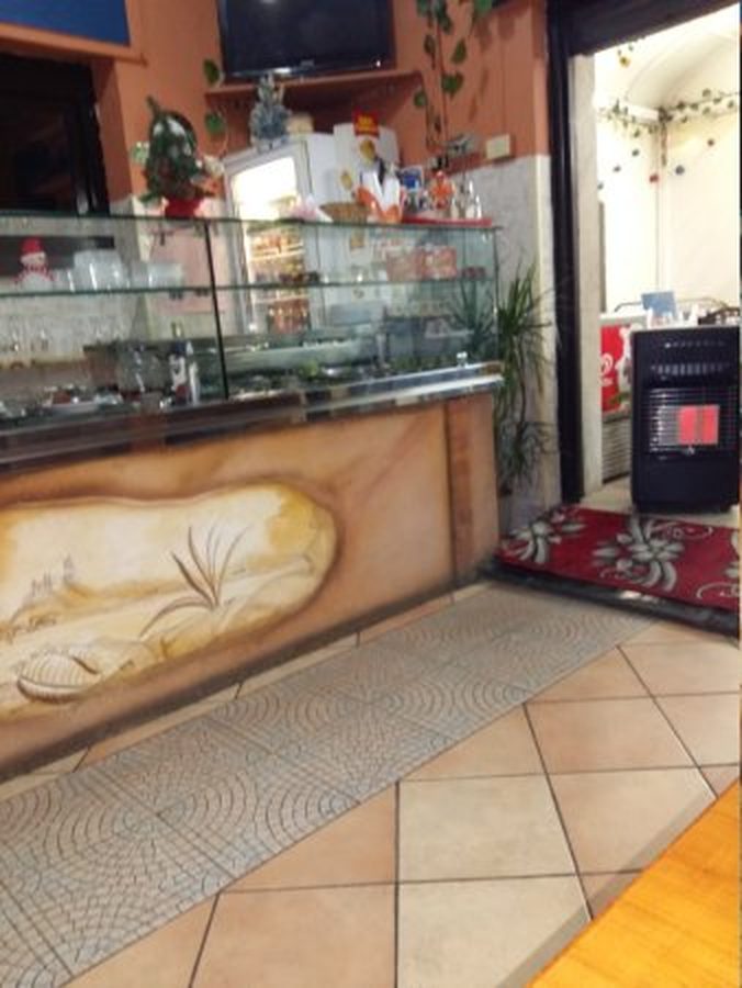 L'interno del locale verso l'uscita: il banco con la vetrina dei fritti e la porta aperta sulla strada.