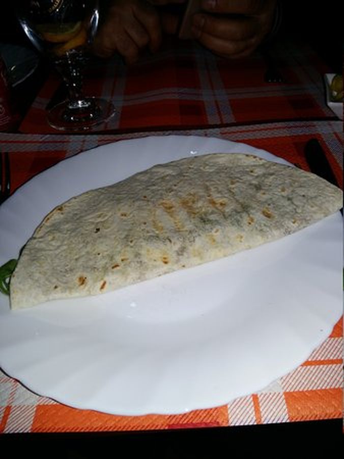 Calzone chiuso appena portato al tavolo, su una tovaglia a quadri arancioni.